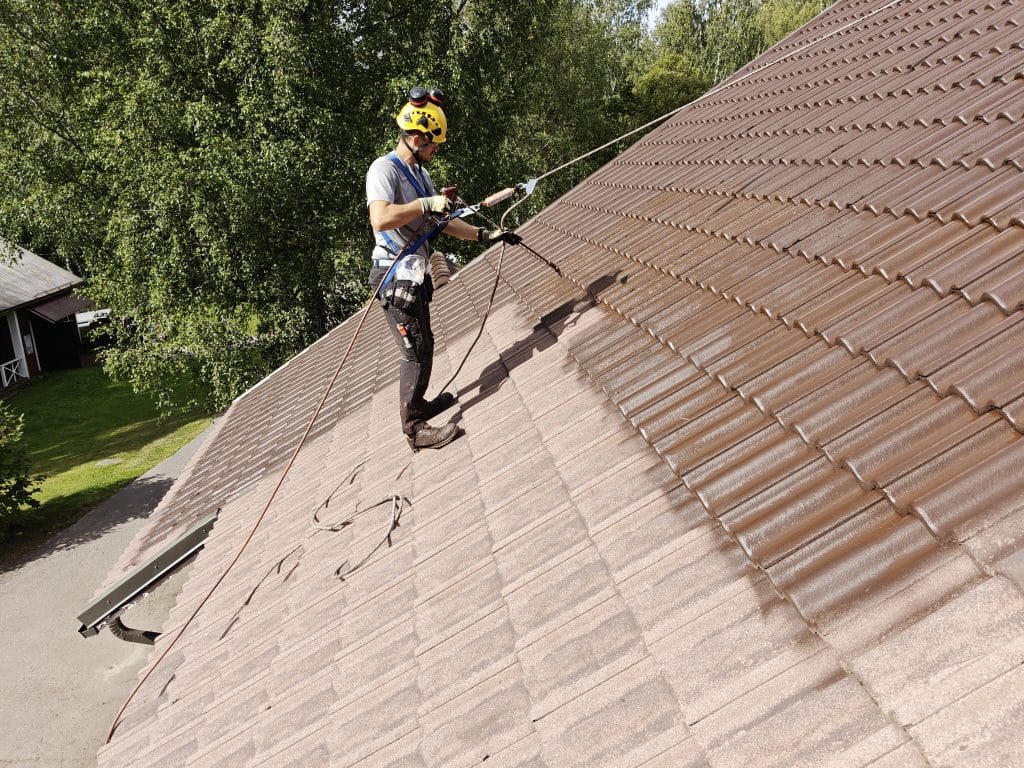 Tiilikaton pinnoitus. Ensimmäisen pinnoite kerroksen levitystä asianmukaisissa suojavarusteissa.